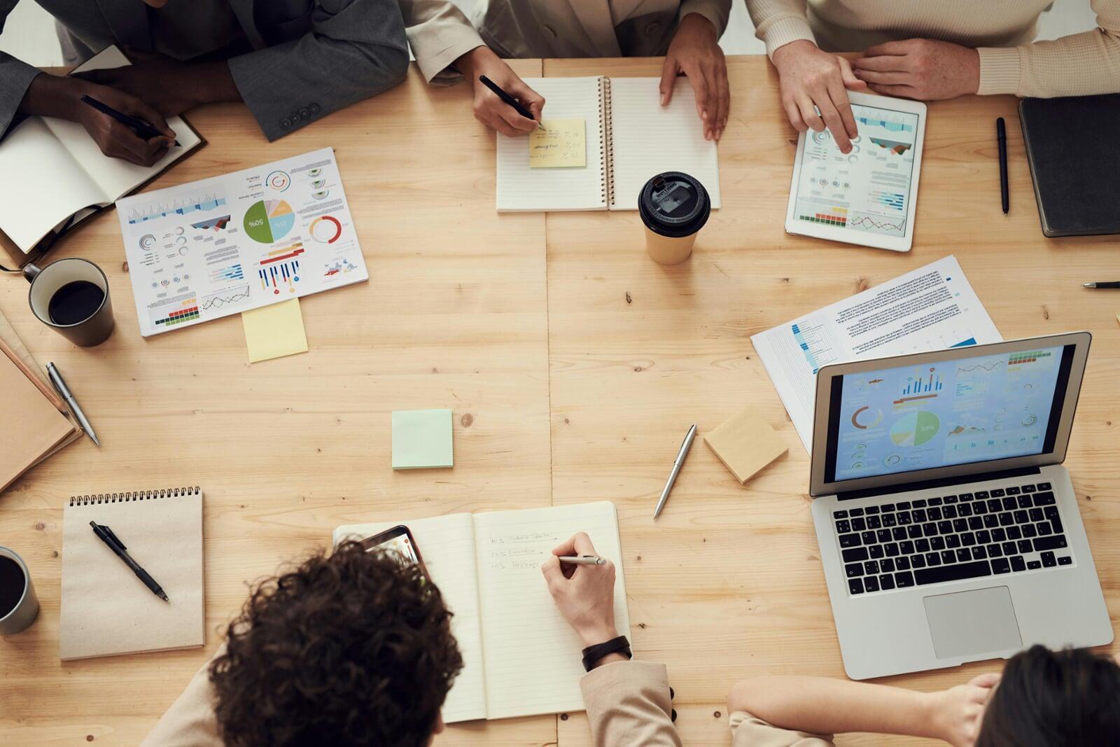 A business team meeting where there is lots of statistics, and people are writing into pads.