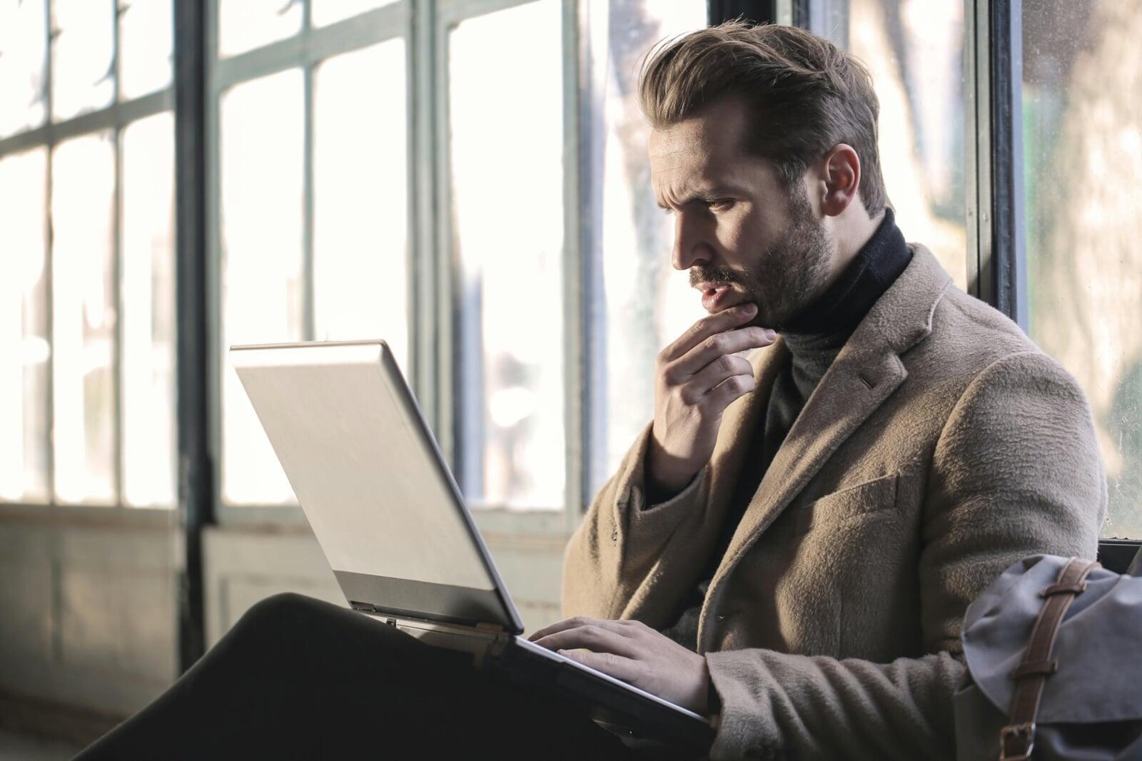 A confused man staring at his laptop screen.