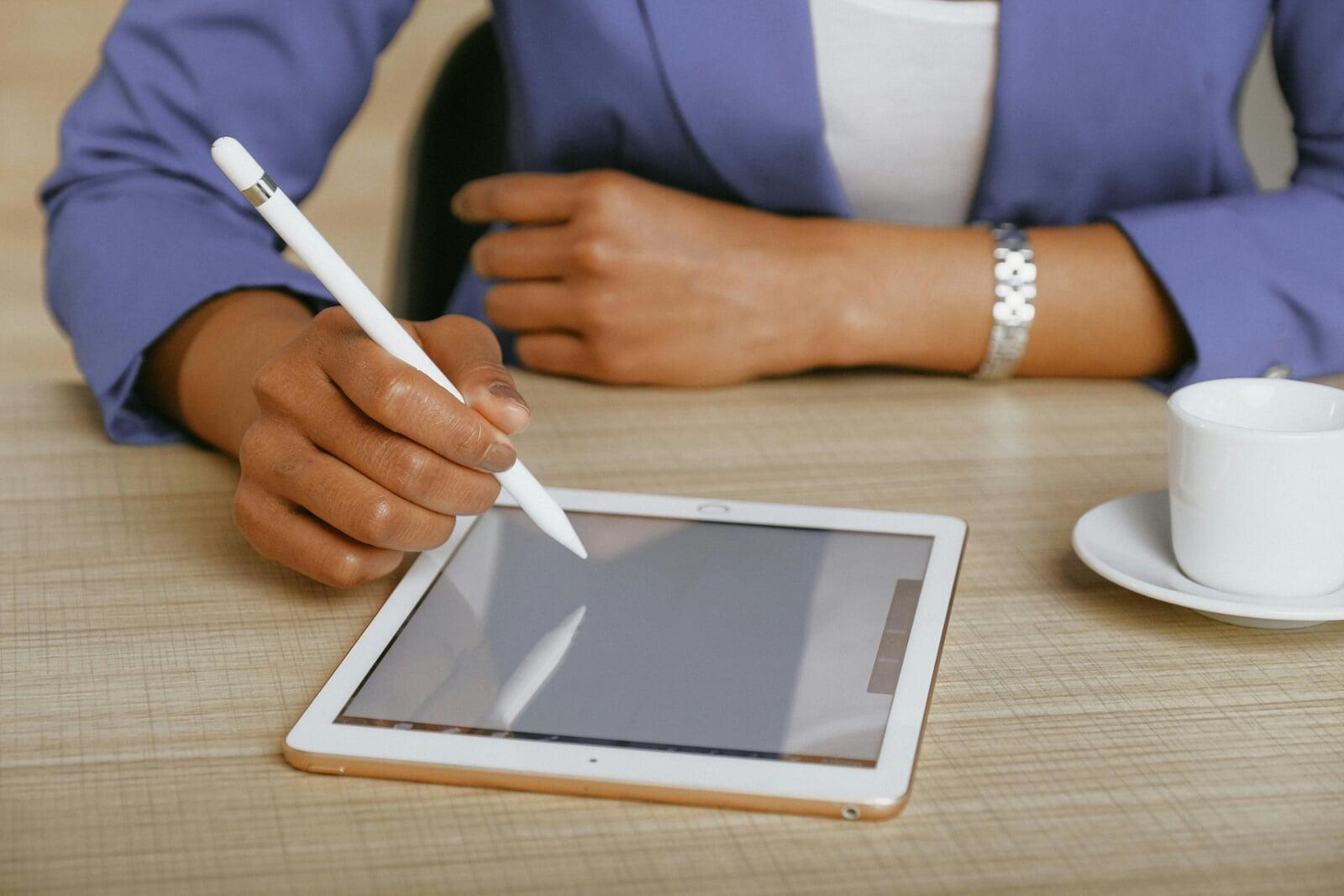 A person with an electronic pen drawing on a tablet.